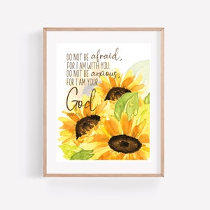 Op de afbeelding: Een aquarel schilderij van zonnebloemen met de tekst "DO NOT BE afraid, FOR I AM WITH YOU. DO NOT BE anxious, FOR I AM YOUR God" gedrukt op een witte achtergrond.