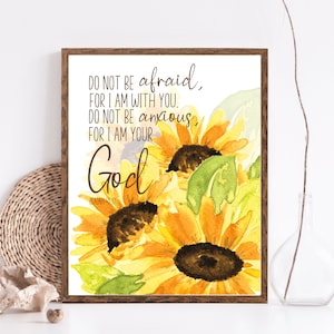 Op de afbeelding: Een aquarel van zonnebloemen met een bijbelvers dat luidt: "Wees niet bang, want Ik ben met je; wees niet verschrikt, want Ik ben jouw God." Het vers is uit Jesaja 41:10.