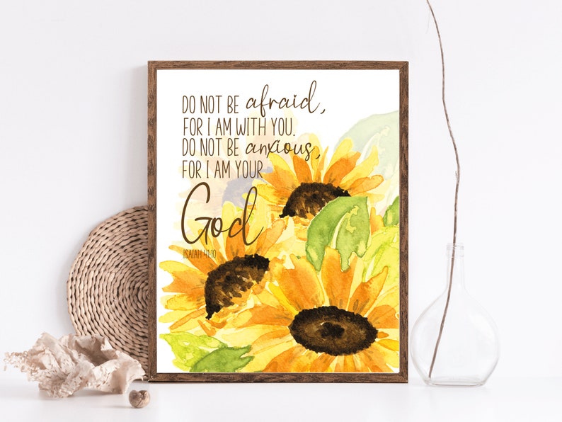 Op de afbeelding: Een aquarel van zonnebloemen met een bijbelvers dat luidt: "Wees niet bang, want Ik ben met je; wees niet verschrikt, want Ik ben jouw God." Het vers is uit Jesaja 41:10.