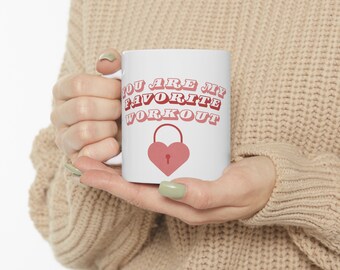 Può includere: Tazza da caffè in ceramica bianca con il testo "You are my favorite workout" in lettere rosa e rosse con una grafica di lucchetto a forma di cuore rosso.