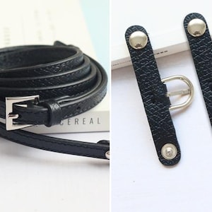 May include: A black leather belt with a silver buckle and two black leather strap adjusters with silver buckles.