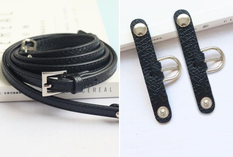 May include: A black leather belt with a silver buckle and two black leather strap adjusters with silver buckles.