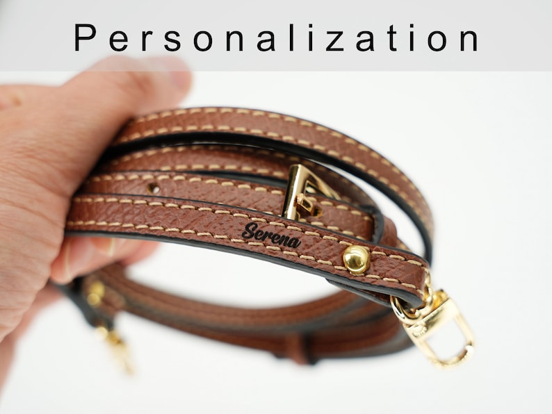 May include: Brown leather strap with a gold buckle and a personalized inscription that reads "Serena".