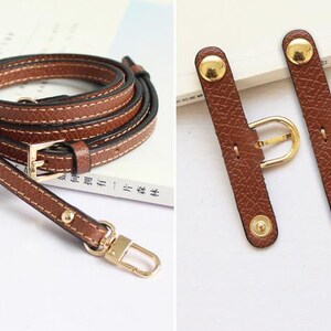 May include: A brown leather strap with gold hardware, including a buckle and two adjustable strap extenders. The strap is designed for a bag or purse.