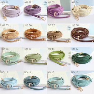 May include: Sixteen coiled leather bag straps in a range of colours, such as lavender, purple, beige, brown, green, and blue. Each strap has gold-coloured metal hardware, including buckles and clasps. The straps are displayed coiled.
