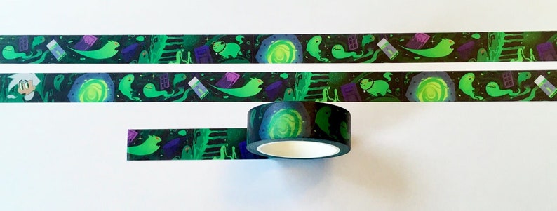 May include: A roll of black and green washi tape with a repeating pattern of ghosts, a portal, and other spooky elements. The tape is rolled up on a spool.