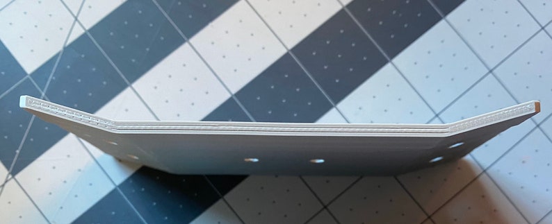 May include: A white, rectangular tray with a slightly curved design. The tray has a series of small holes and a textured edge. The tray is made of a light-colored material and appears to be new.