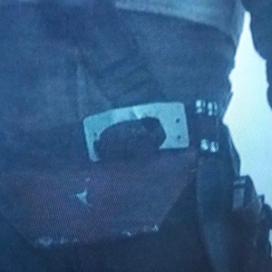 May include: Close-up of a dark blue utility belt with a silver buckle and a black pouch. The belt appears to be made of a durable fabric, and the buckle has a rectangular shape.