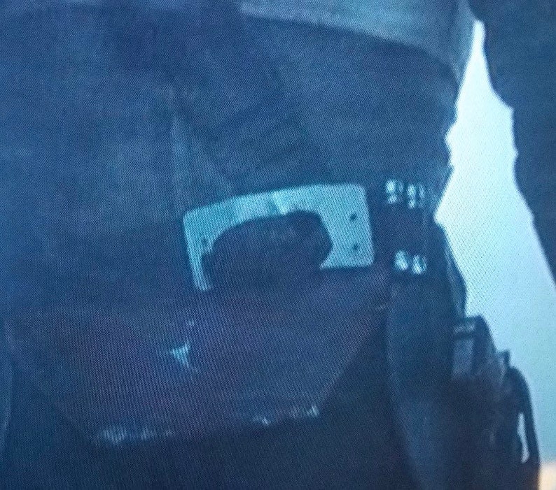 May include: Close-up of a dark blue utility belt with a silver buckle and a black pouch. The belt appears to be made of a durable fabric, and the buckle has a rectangular shape.