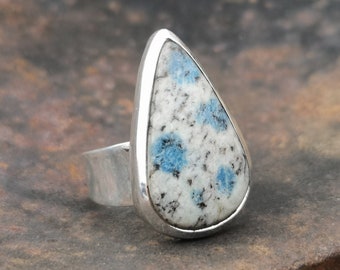 Peut inclure: Une bague en forme de larme avec une pierre mouchetée de bleu et de blanc sertie dans une bande argentée.