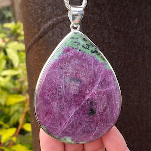 May include: A teardrop-shaped pendant featuring a green and pink gemstone set in sterling silver.