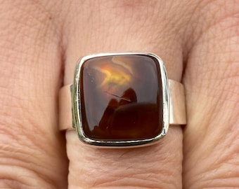 May include: A silver ring with a large, square, brown agate gemstone. The gemstone has a swirling pattern of brown, orange, and yellow.