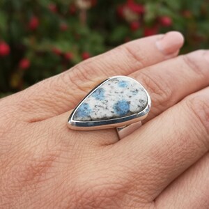 May include: A silver ring with a teardrop-shaped blue and white stone set in a silver bezel.