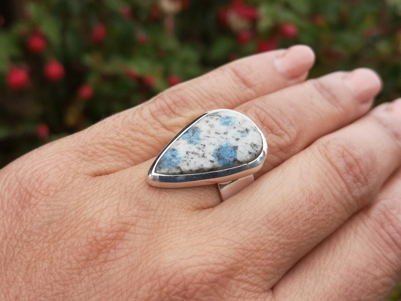May include: A silver ring with a teardrop-shaped blue and white stone set in a silver bezel.