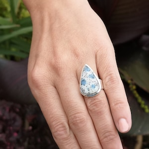 May include: A silver ring with a teardrop-shaped blue and white stone.