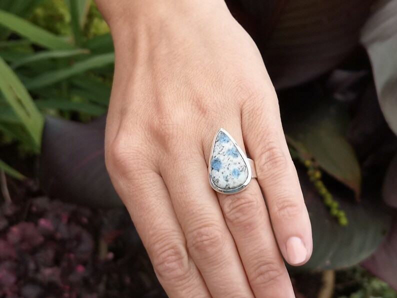 May include: A silver ring with a teardrop-shaped blue and white stone.