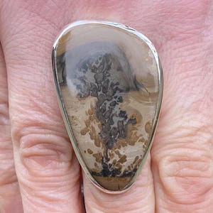 May include: A set of three ceramic mugs with a speckled, cream-colored glaze. Each mug features a different hand-painted floral design in shades of blue, green, and yellow. The mugs have a simple, rounded shape and a comfortable handle.