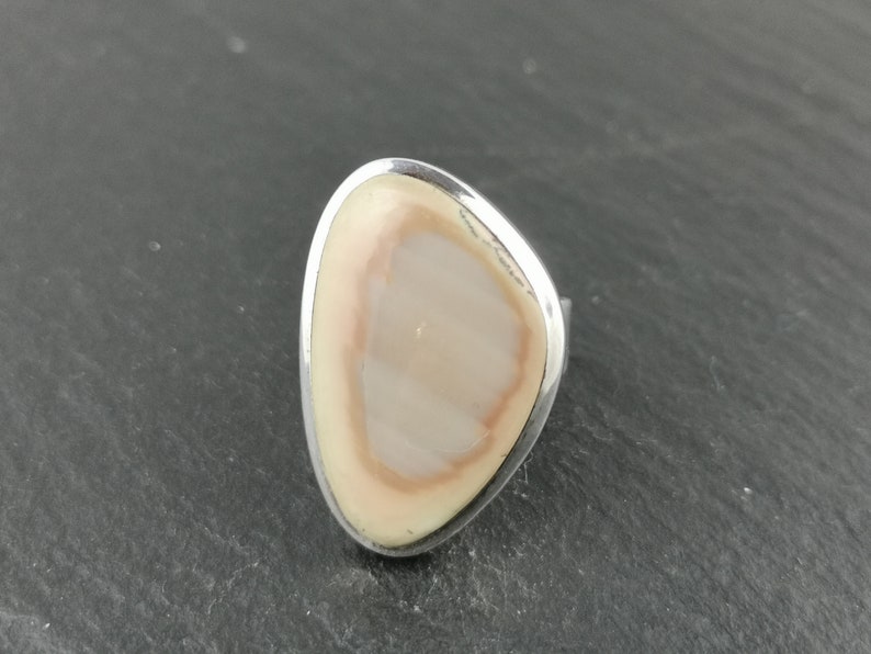 K&ouml;nnte beinhalten: Ein silberner Ring mit einem ovalen, hellbraunen Stein in der Mitte.