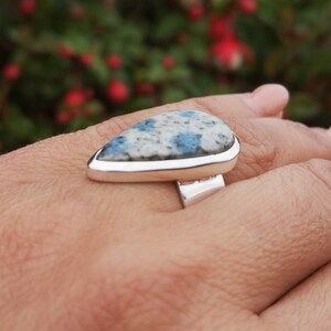 May include: A silver ring with a teardrop-shaped blue and white stone set in a silver bezel.