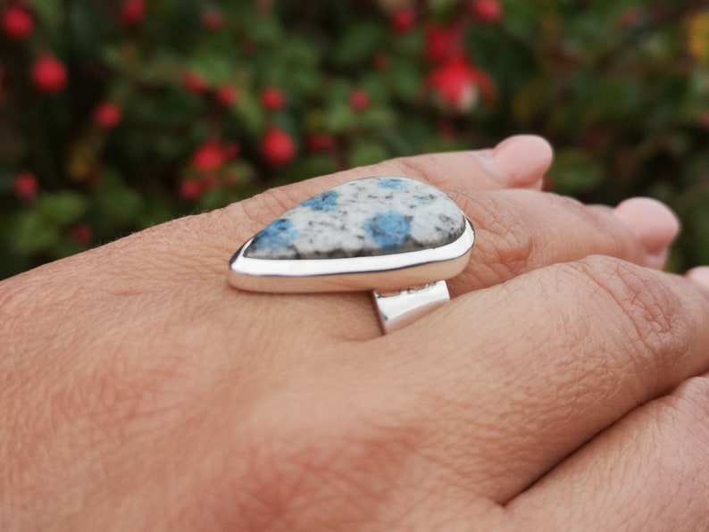 May include: A silver ring with a teardrop-shaped blue and white stone set in a silver bezel.