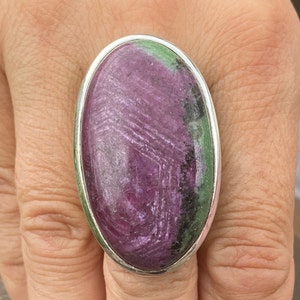 May include: A silver ring featuring a large oval green and purple gemstone.