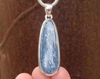 May include: A teardrop-shaped pendant with a blue stone and a silver-colored metal frame. The stone has a marbled appearance with shades of blue and white. The pendant hangs from a silver chain.