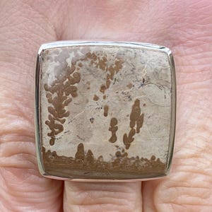 May include: A set of three ceramic mugs with a speckled, matte finish. The mugs are in shades of cream, light gray, and dark gray. Each mug has a simple, minimalist design and a rounded handle.