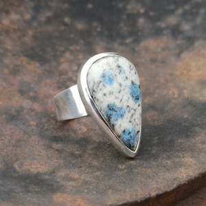 May include: A silver ring with a teardrop-shaped blue and white stone set in a silver bezel.