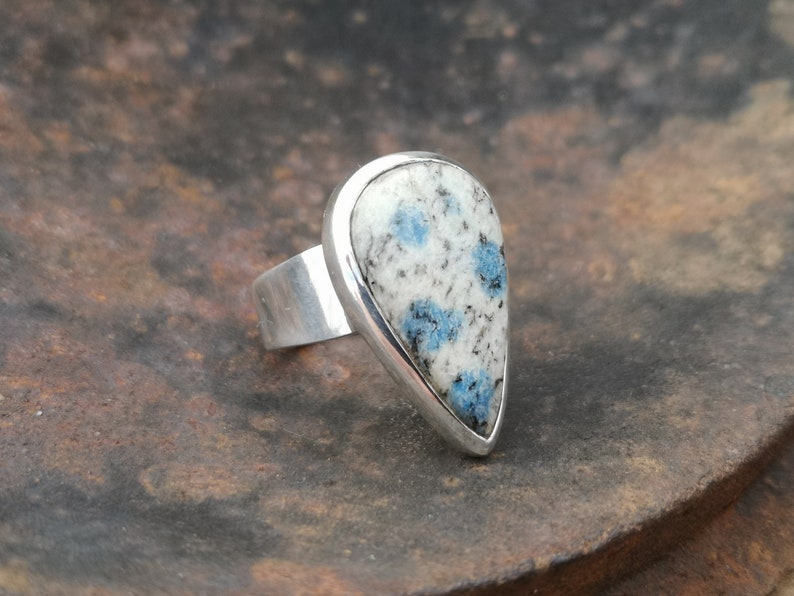 May include: A silver ring with a teardrop-shaped blue and white stone set in a silver bezel.