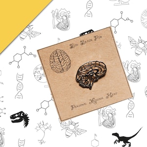 Könnte beinhalten: Ein bronzefarbener Gehirn-Pin auf einer Karte aus Kraftpapier mit dem Text "Big Brain Pin" und "Personal Message Here". Der Hintergrund zeigt ein sich wiederholendes Muster von wissenschaftlichen Illustrationen in Schwarz und Weiß.
