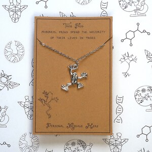 May include: A silver tree frog pendant necklace on a brown card with the text "TREE FROG" and "ARBOREAL FROGS SPEND THE MAJORITY OF THEIR LIVES IN TREES." The card also has the text "PERSONAL MESSAGE HERE".