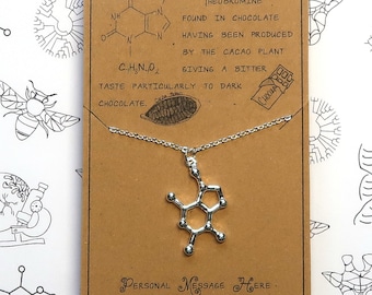 May include: A silver necklace with a pendant shaped like the chemical structure of theobromine, a compound found in chocolate. The card reads "Theobromine, found in chocolate, having been produced by the cacao plant, giving a bitter taste particularly to dark chocolate."  The card also has a small illustration of a chocolate bar.