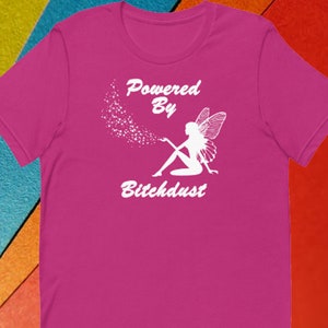 May include: Pink t-shirt with a white graphic of a fairy with wings and the text "Powered By Bitchdust".