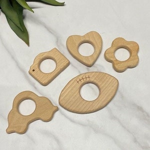 wooden teether for infants provide comfort to gums. Various shapes available like football, flower, heart, camera and car.