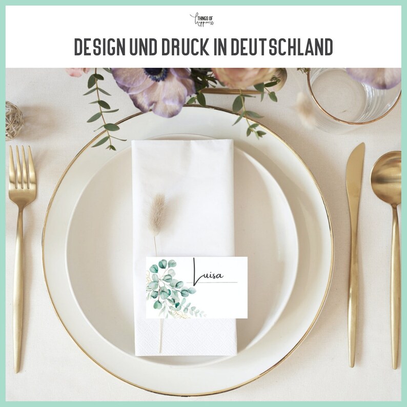 May include: A white place card with a green and gold floral design and the name "Luisa" written in black ink. The place card is on a white napkin on a white plate with a gold rim.
