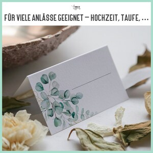May include: White place card with a green watercolor eucalyptus leaf design. The text "F&Uuml;R VIELE ANL&Auml;SSE GEEIGNET - HOCHZEIT, TAUFE,..." is at the top of the image.