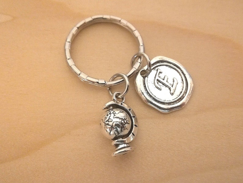 Puede incluir: Llavero de plata con un encanto de globo terr&aacute;queo y un encanto de letra 'E'. El encanto de globo terr&aacute;queo est&aacute; detallado con continentes y oc&eacute;anos. El encanto de letra 'E' es de estilo sello de cera.