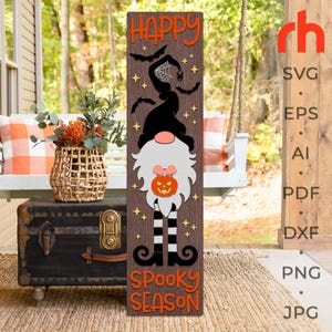 May include: A wooden sign with a gnome wearing a witch hat and holding a pumpkin. The sign says "Happy Spooky Season".