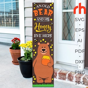 May include: A wooden sign with a brown bear holding a jar of honey. The sign reads "An old bear and his honey live here" with yellow bees and honeycomb designs.