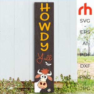 以下が含まれることがあります： 「HOWDY Y'all」の文字が黄色とオレンジ色で書かれた、縦型の木製看板。下部には、口にデイジーを持った漫画の牛がいます。看板は濃い茶色で、屋外に展示されています。
