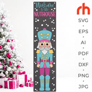 May include: A wooden sign featuring a colorful nutcracker soldier with the text "Welcome to the Nuthouse." The sign is predominantly blue, pink, and gold, with a dark gray background and white accents. The sign is a festive decoration.