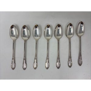 May include: Set of six silver teaspoons with ornate handles. The spoons are polished and shiny.