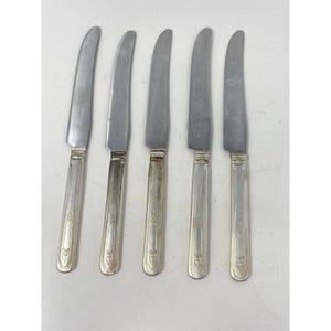 May include: Five silver dinner knives with ornate handles.