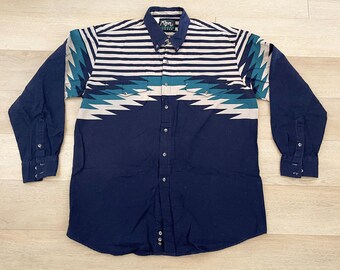 May include: A long-sleeved blue and white patterned shirt with a white collar and button closure. The shirt has a geometric pattern with teal accents and the text "Arrow" on the left side of the collar.