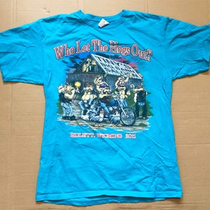 May include: A turquoise blue t-shirt with a cartoon image of a biker bar with the text "Who Let The Hogs Out?" and "Billetta Wyoming 2001".