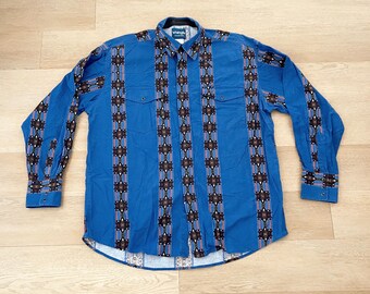 May include: A blue long-sleeve shirt with a geometric pattern in brown, white, and red. The shirt has a button-down collar and two chest pockets.