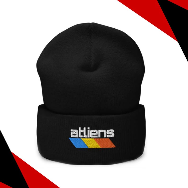 May include: Black beanie hat with the word "atliens" embroidered in white, above a horizontal stripe of blue, yellow, and orange. The hat is made of a soft material and is suitable for cold weather.
