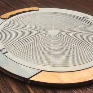 May include: A wooden tray with a circular design featuring concentric circles. The tray has a light blue finish and a natural wood rim. A handle is attached to the side of the tray.