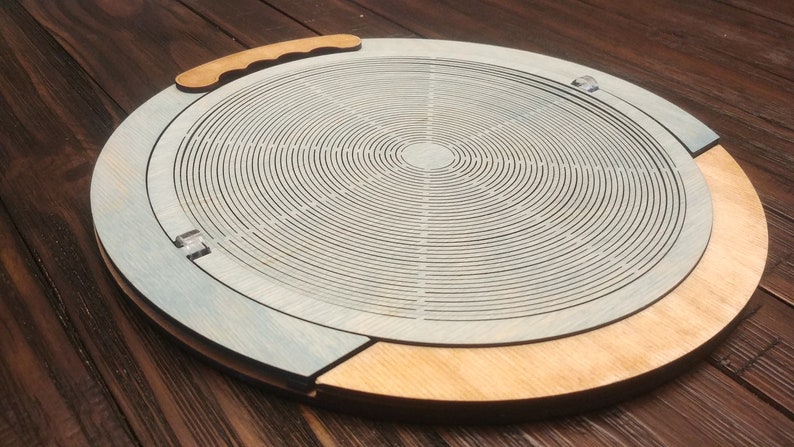 May include: A wooden tray with a circular design featuring concentric circles. The tray has a light blue finish and a natural wood rim. A handle is attached to the side of the tray.