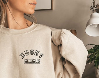 Może przedstawiać: Beżowa bluza z napisem "HUSKY MAMA" w czarnych, obwiedzionych literach.